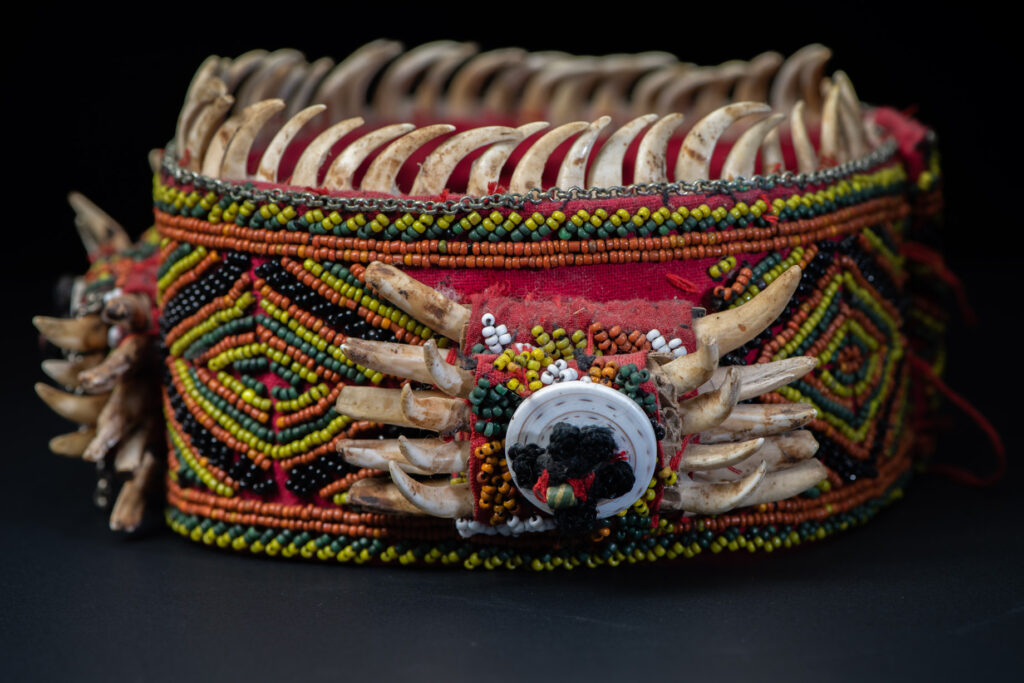 Women's headdress from the Paiwan tribe, made of green, yellow, red, and black beads arranged in geometric patterns, and topped with boar tusks.