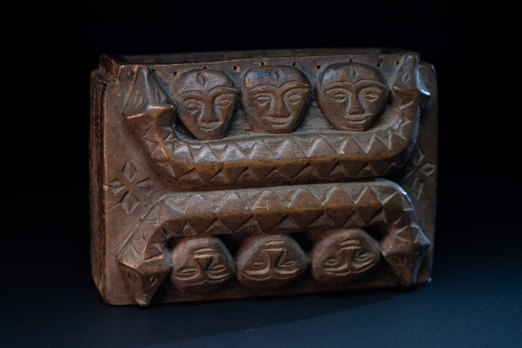 Paiwan tribe ancient shaman box in wood carved with two designs mirrored of three human head set up on a two heads snake .