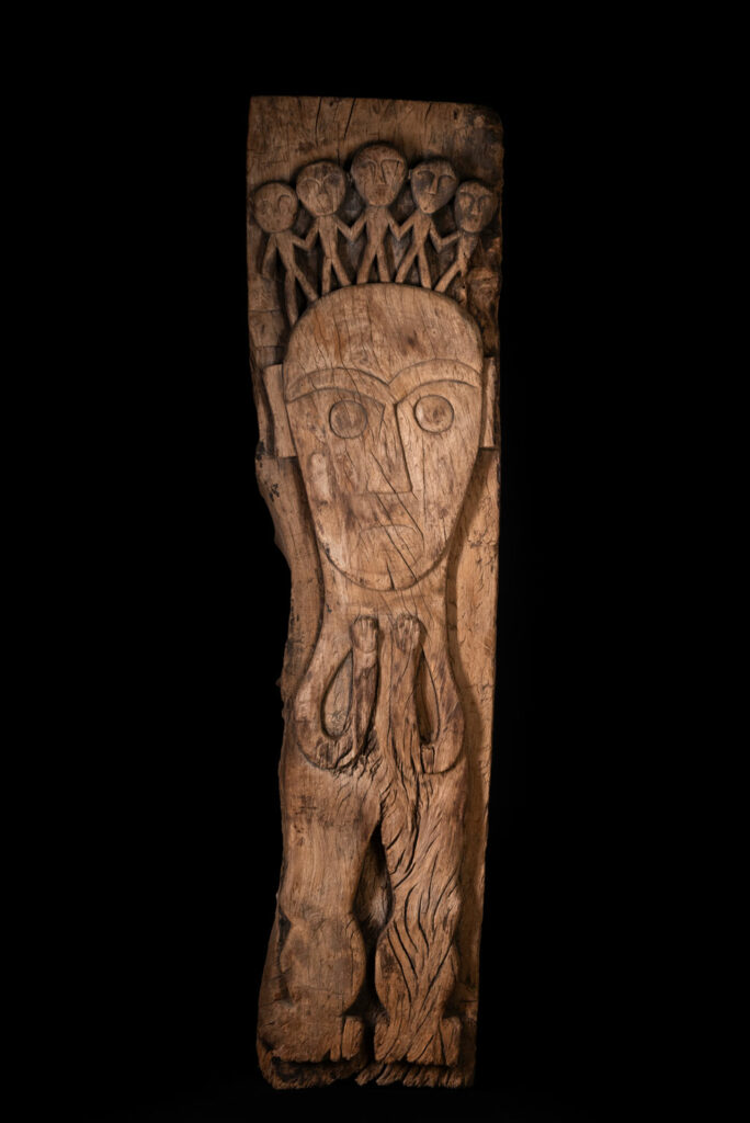 Rare and massive 19th-century Paiwan tribe shamanic ancestor panel, carved with a thick relief depicting a shaman with an oversized head crowned with multiple human faces — symbolizing his responsibility over the tribe’s spiritual and physical well-being.