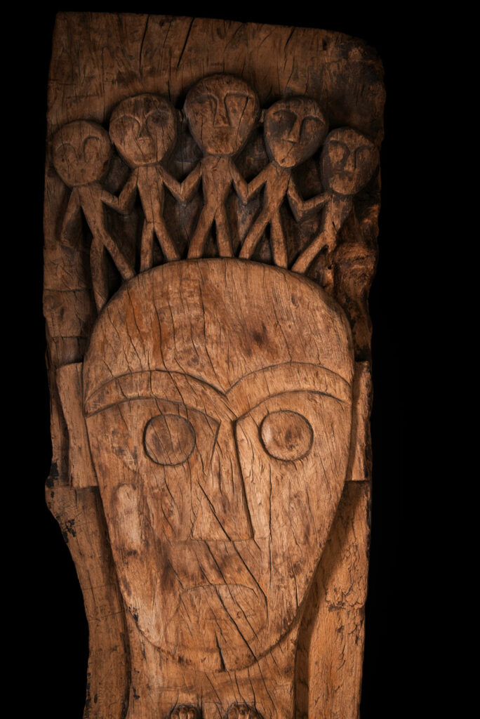 Rare and massive 19th-century Paiwan tribe shamanic ancestor panel, carved with a thick relief depicting a shaman with an oversized head crowned with multiple human faces — symbolizing his responsibility over the tribe’s spiritual and physical well-being.