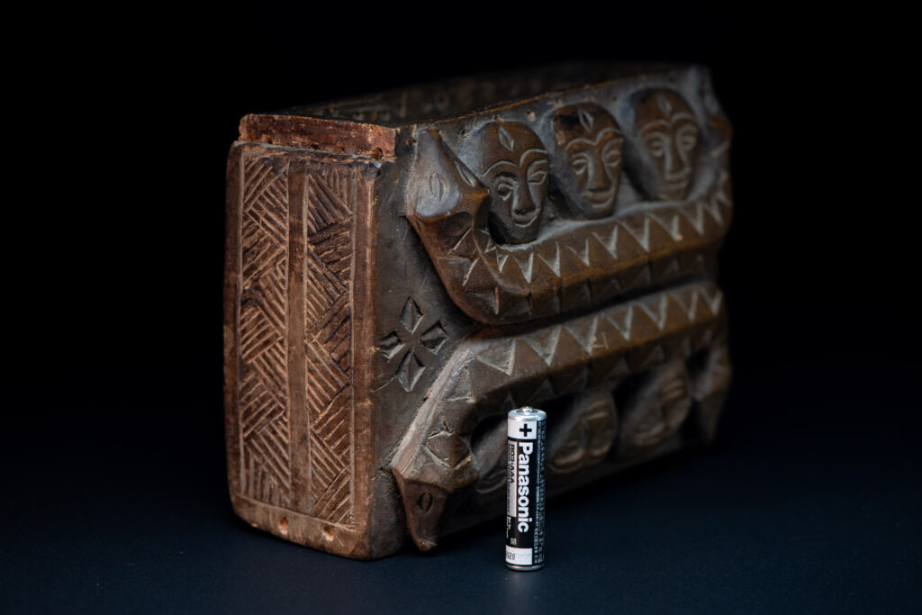 Paiwan tribe ancient shaman box in wood carved with two designs mirrored of three human head set up on a two heads snake .