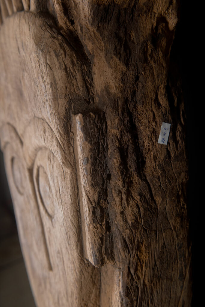Rare and massive 19th-century Paiwan tribe shamanic ancestor panel, carved with a thick relief depicting a shaman with an oversized head crowned with multiple human faces — symbolizing his responsibility over the tribe’s spiritual and physical well-being.