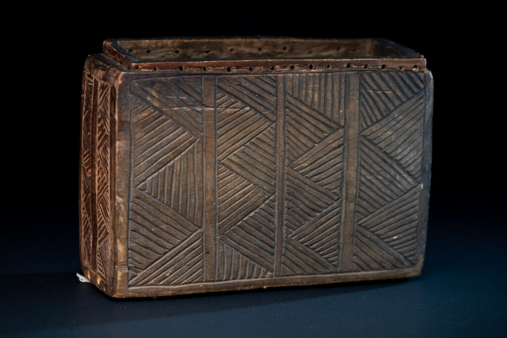Paiwan tribe ancient shaman box in wood carved with two designs mirrored of three human head set up on a two heads snake .