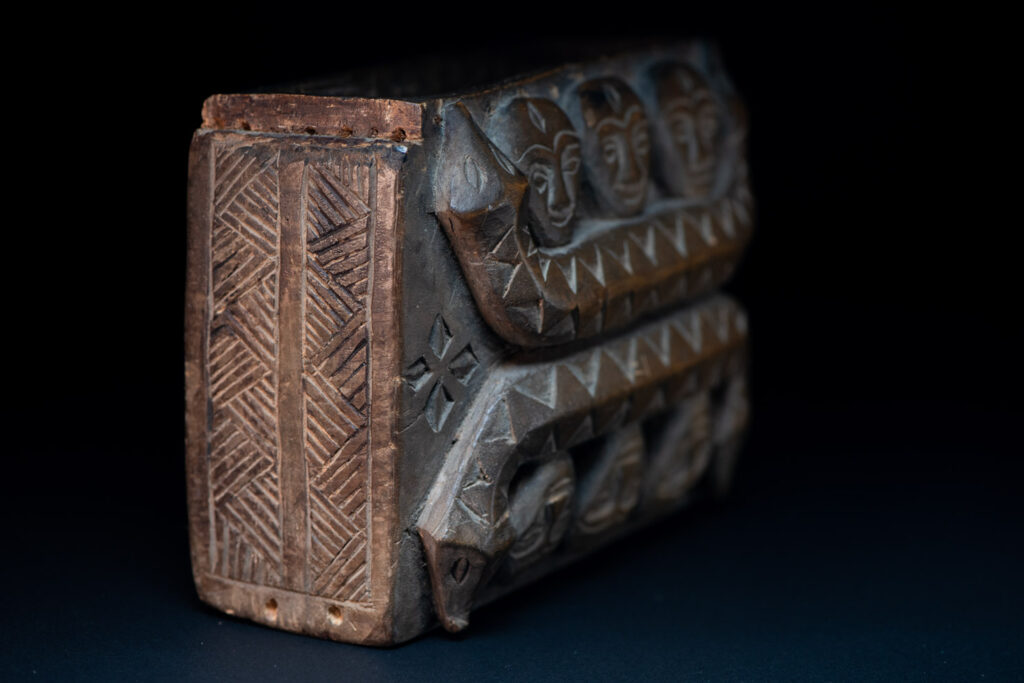 Paiwan tribe ancient shaman box in wood carved with two designs mirrored of three human head set up on a two heads snake .