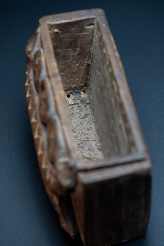 Paiwan tribe ancient shaman box in wood carved with two designs mirrored of three human head set up on a two heads snake .
