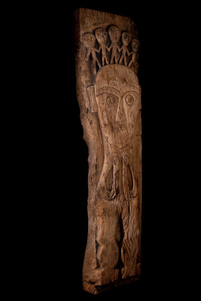 Rare and massive 19th-century Paiwan tribe shamanic ancestor panel, carved with a thick relief depicting a shaman with an oversized head crowned with multiple human faces — symbolizing his responsibility over the tribe’s spiritual and physical well-being.