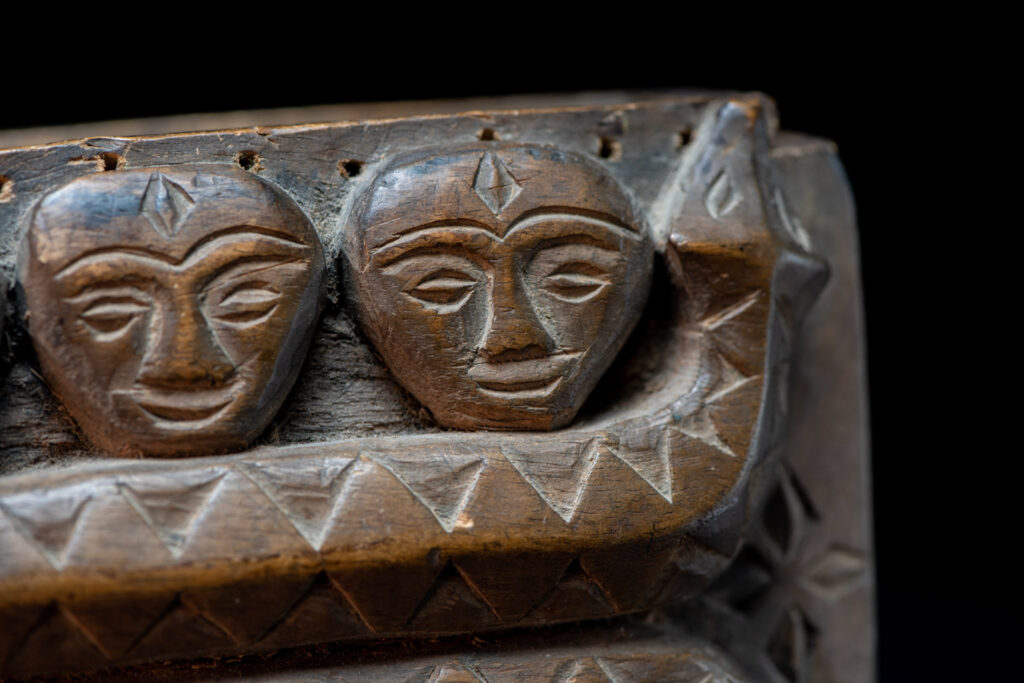 Paiwan tribe ancient shaman box in wood carved with two designs mirrored of three human head set up on a two heads snake .