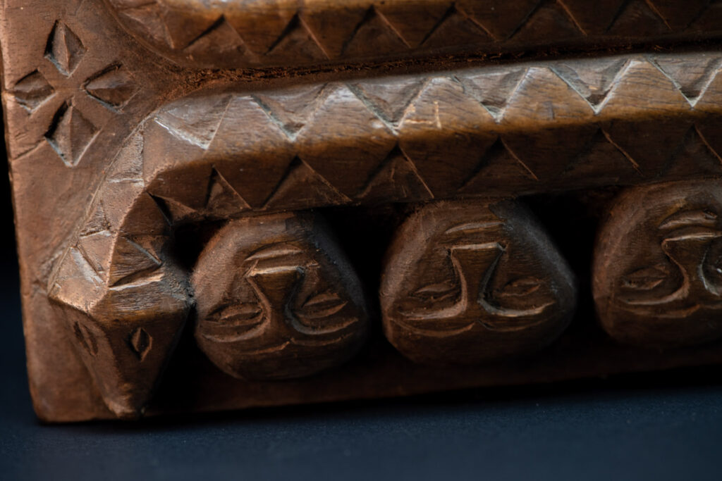 Paiwan tribe ancient shaman box in wood carved with two designs mirrored of three human head set up on a two heads snake .
