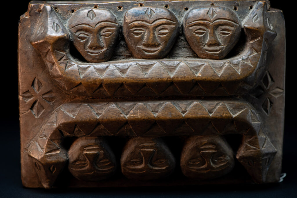 Paiwan tribe ancient shaman box in wood carved with two designs mirrored of three human head set up on a two heads snake .