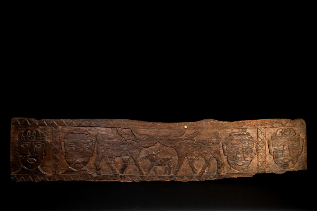 Ancient 19 century Paiwan tribe house eave carved with four human faces and three deers, two big and one small in the middle.