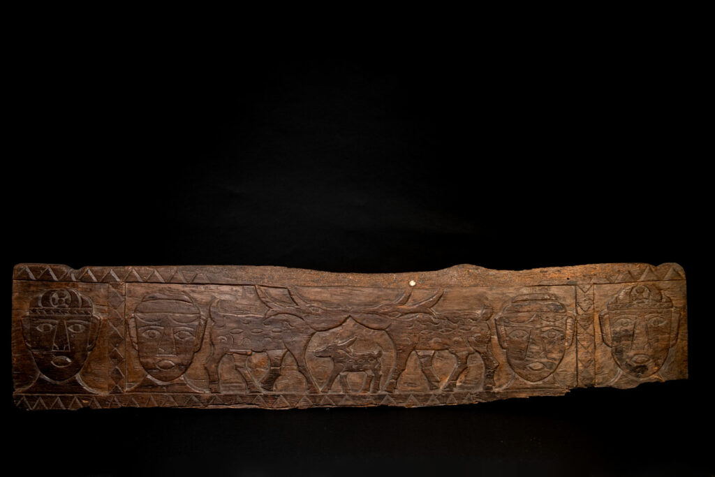 Ancient 19 century Paiwan tribe house eave carved with four human faces and three deers, two big and one small in the middle.