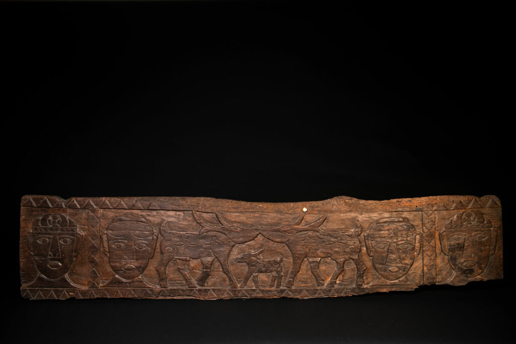 Ancient 19 century Paiwan tribe house eave carved with four human faces and three deers, two big and one small in the middle.