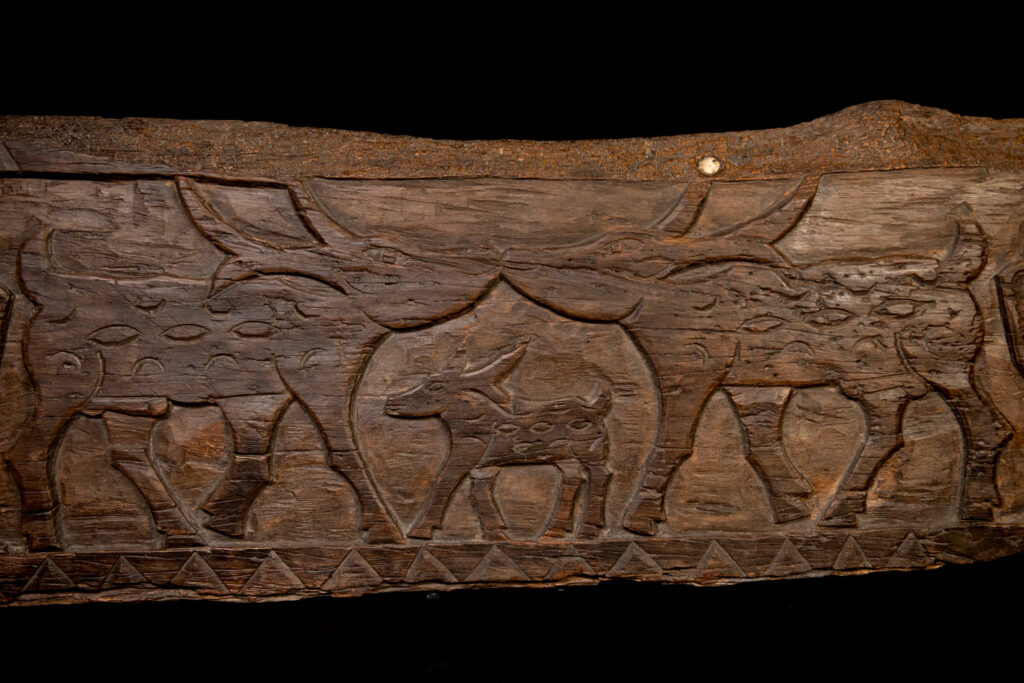 Ancient 19 century Paiwan tribe house eave carved with four human faces and three deers, two big and one small in the middle.