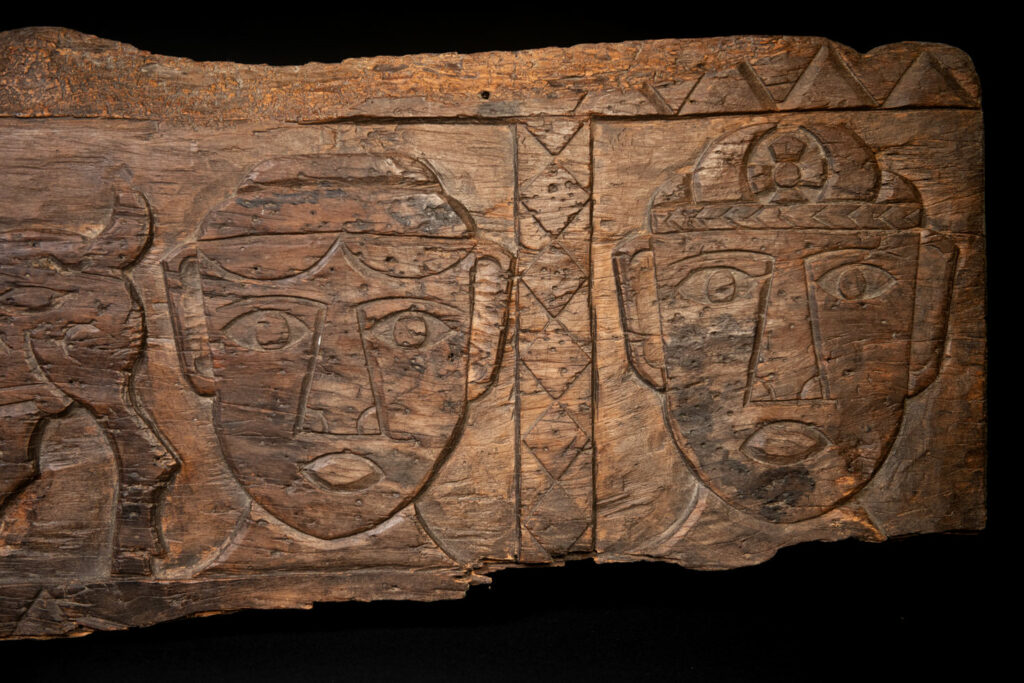 Ancient 19 century Paiwan tribe house eave carved with four human faces and three deers, two big and one small in the middle.