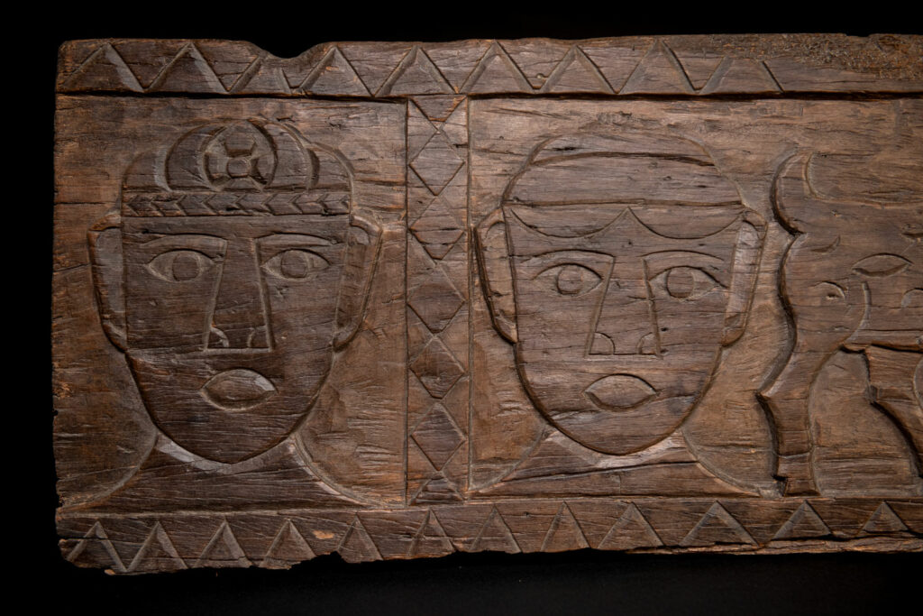 Ancient 19 century Paiwan tribe house eave carved with four human faces and three deers, two big and one small in the middle.