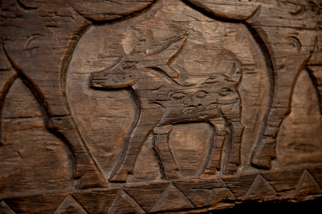 Ancient 19 century Paiwan tribe house eave carved with four human faces and three deers, two big and one small in the middle.
