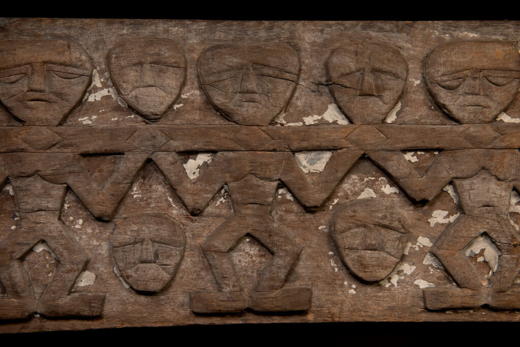Paiwan tribe house eave carved with warriors drinking millet wine from a double cup — a symbol of unity — after a victory. Taiwan