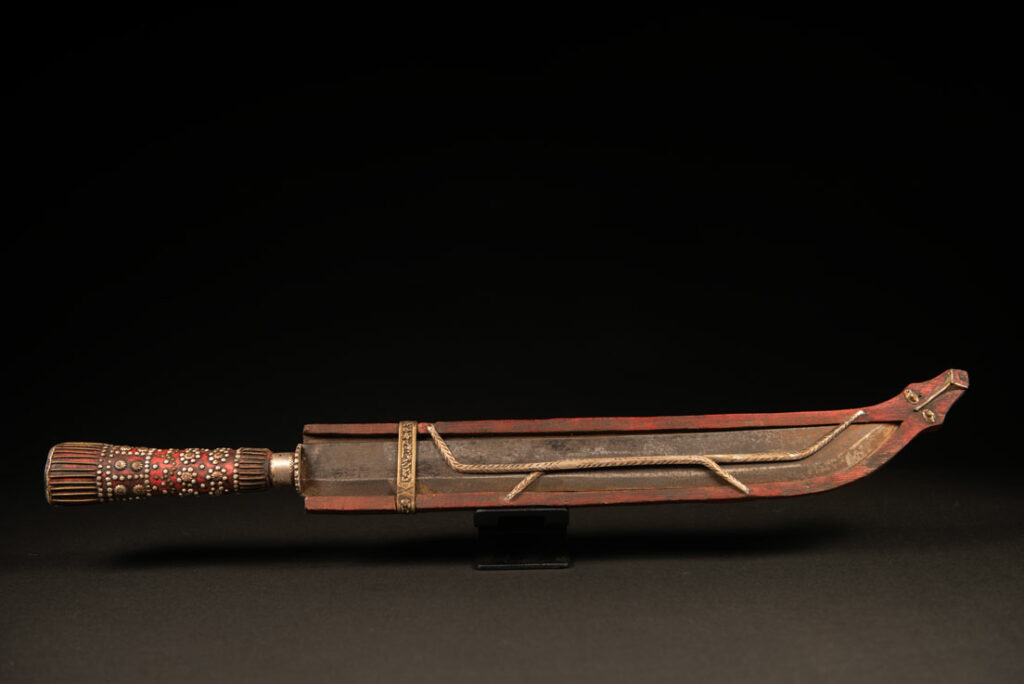 Typical Rukai-style sword with a wooden handle inlaid , steel wire and nail heads. ,The straight blade is long, and the scabbard is flat .