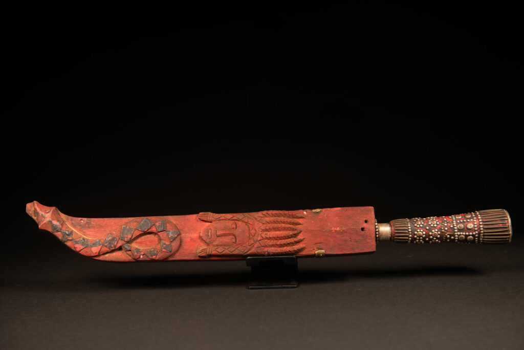 Typical Rukai-style sword with a wooden handle inlaid , steel wire and nail heads. ,The straight blade is long, and the scabbard is flat .