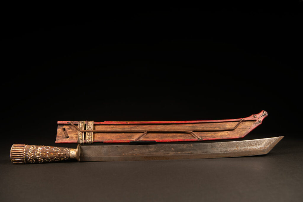 Typical Rukai-style sword with a wooden handle inlaid with steel wire and nail heads. The guard is made from a Chinese coin.