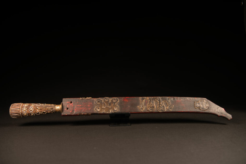 Typical Rukai-style sword with a wooden handle inlaid with steel wire and nail heads. The guard is made from a Chinese coin.