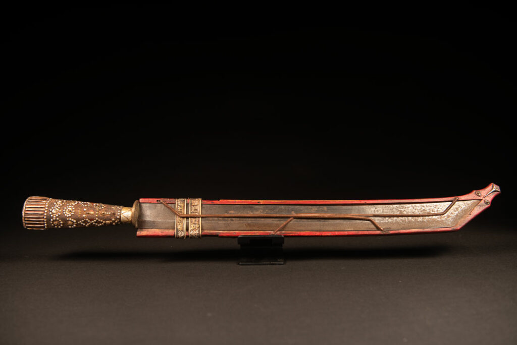 Typical Rukai-style sword with a wooden handle inlaid with steel wire and nail heads. The guard is made from a Chinese coin.