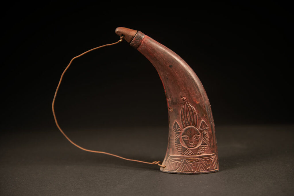 Powder flask from the Rukai tribe, made from a horn sealed at the base with a wooden plug. the body is carved on 2 sides and tint in red .
