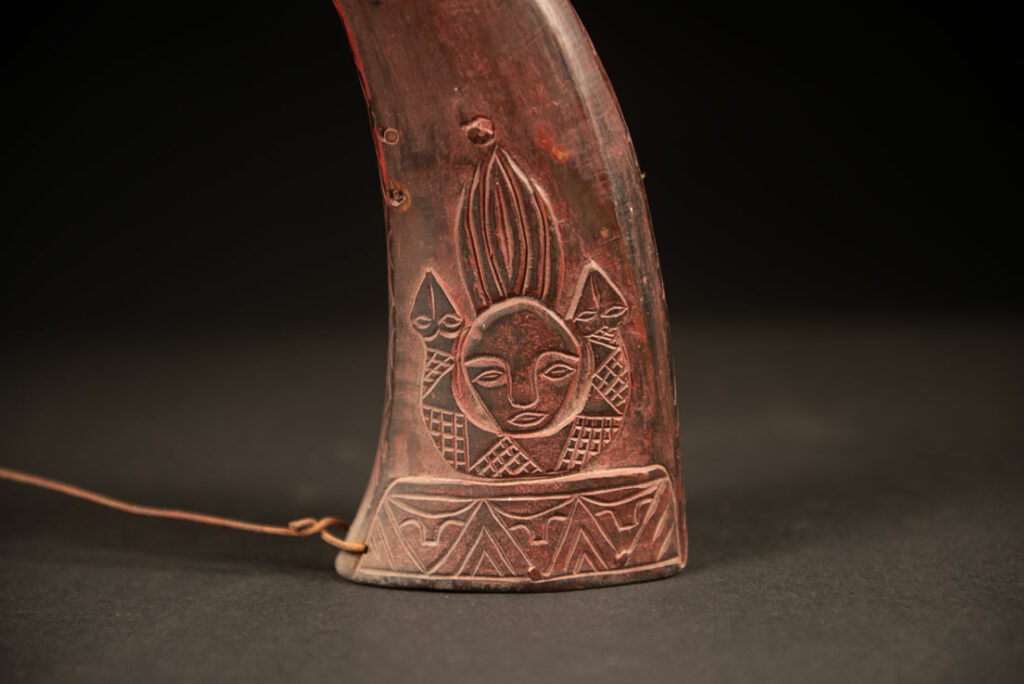 Powder flask from the Rukai tribe, made from a horn sealed at the base with a wooden plug. the body is carved on 2 sides and tint in red .
