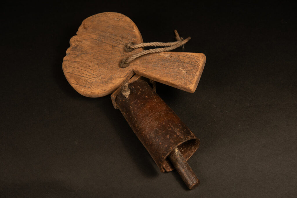 Rukai tribe alarm bell showing a wooden handle shaped with a human face linked with a cylindrical bell .