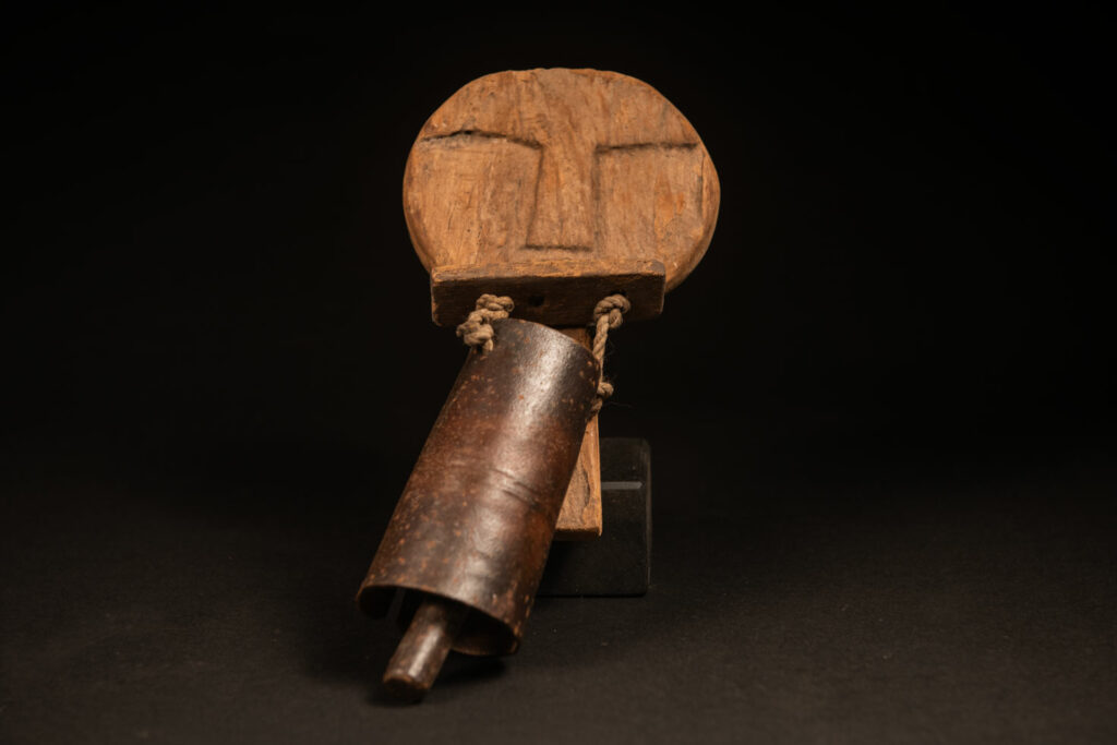 Rukai tribe alarm bell showing a wooden handle shaped with a human face linked with a cylindrical bell .