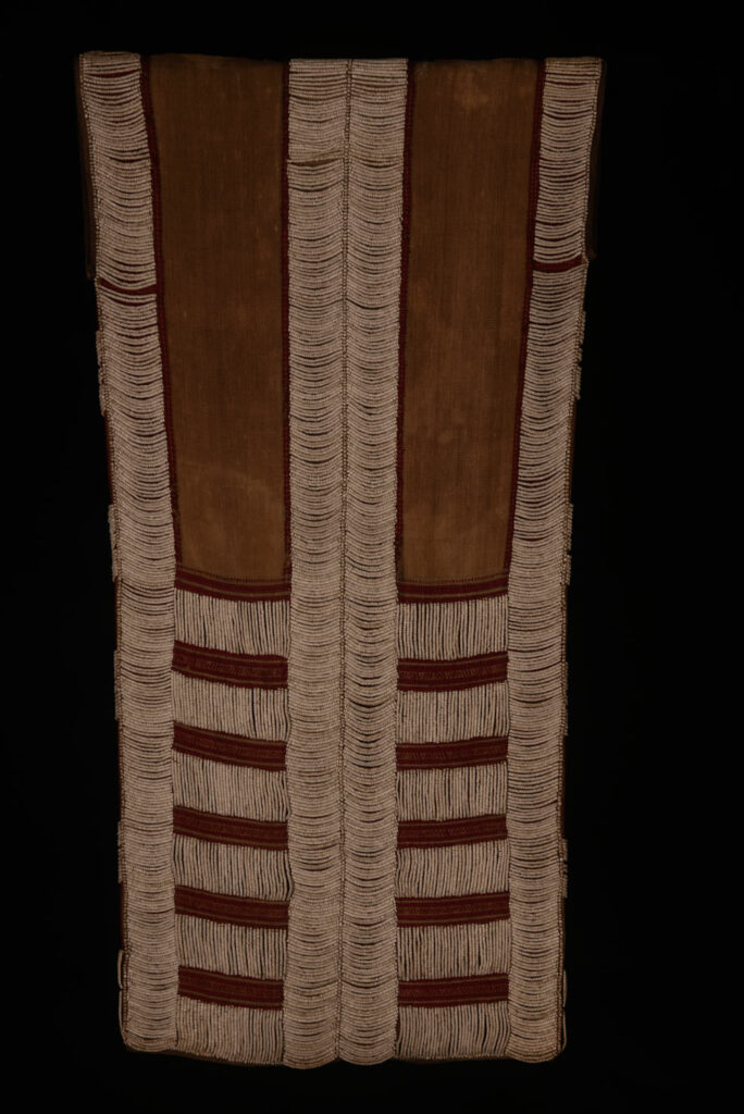Long Atayal tribe sleeveless tunic with an open front and no collar. Made from linen and decorated with dark red wool, its most striking feature lies in the elaborate use of cylindrical clam-shell beads, which are carefully embedded into the fabric in both horizontal and vertical alignments.