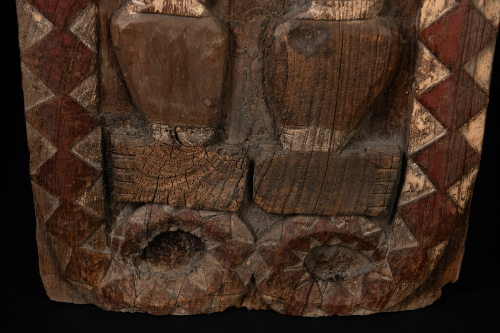 Panel from the Paiwan tribe depicting an ancestor in ceremonial attire, wearing a headdress adorned with eagle feathers. The panel is painted in red and white.