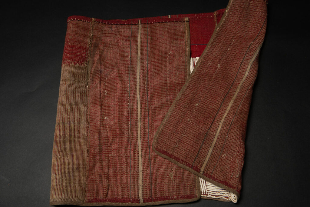 This beaded skirt from Attayal tribe is a piece of 89 cm long and 42 wide linen woven and embroidered with white shell beads. The white beads are made from giant clams. The Patterns are horizontal and vertical stripes . The upper part ( 14 cm ) is not beaded,