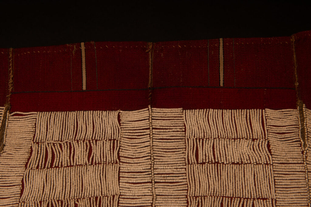 This beaded skirt from Attayal tribe is a piece of 89 cm long and 42 wide linen woven and embroidered with white shell beads. The white beads are made from giant clams. The Patterns are horizontal and vertical stripes . The upper part ( 14 cm ) is not beaded,