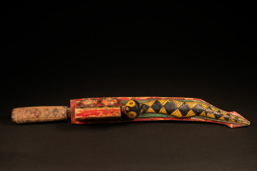 Paiwan tribe sword painted and carved with snake and human face .
