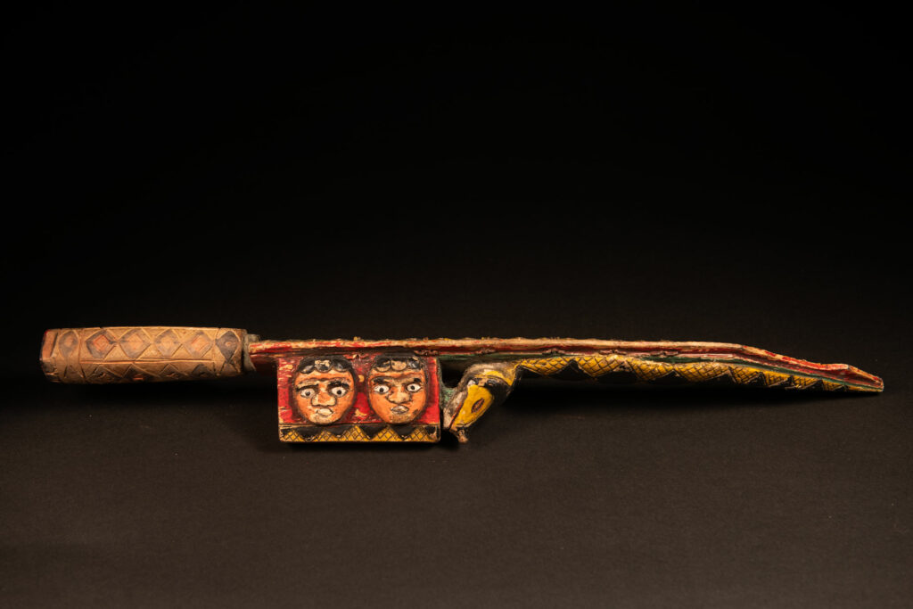 Paiwan tribe sword painted and carved with snake and human face .