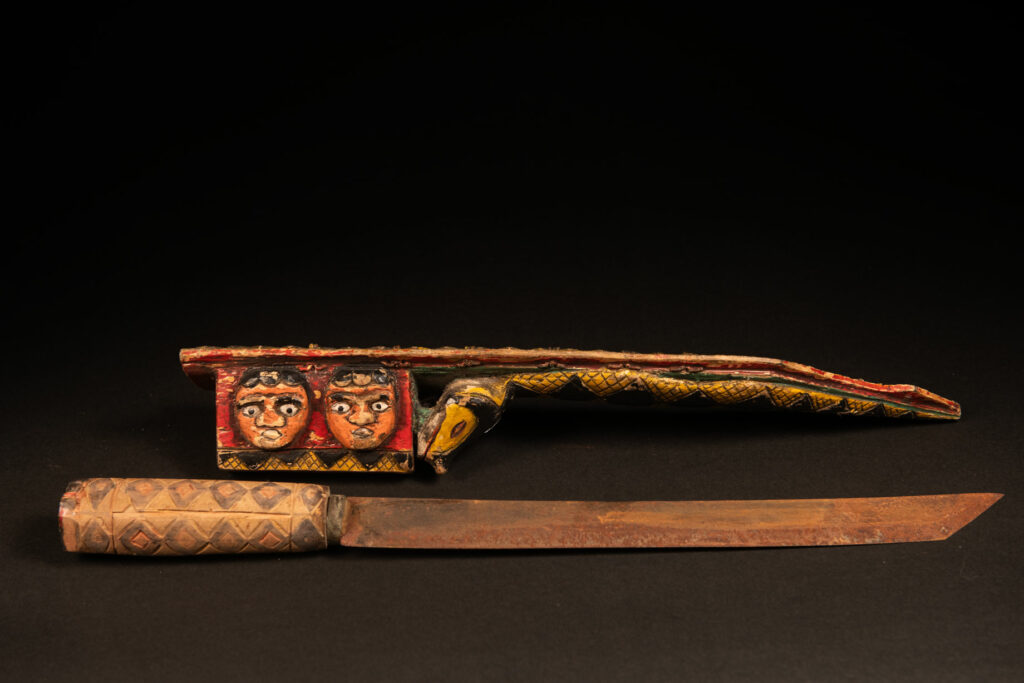 Paiwan tribe sword painted and carved with snake and human face .