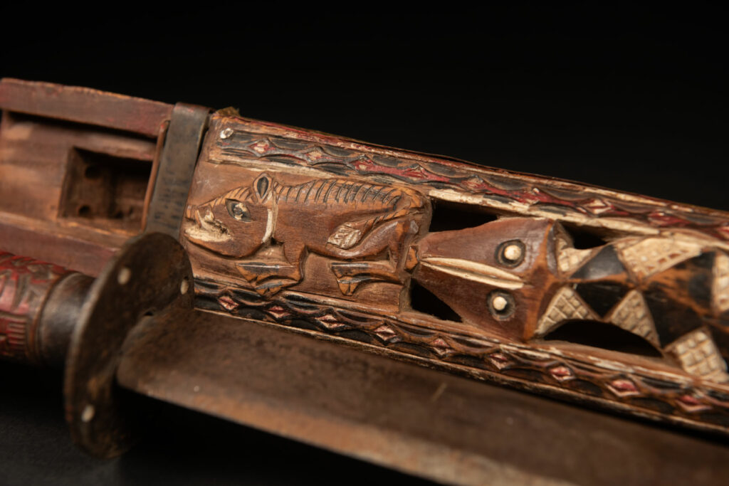This ceremonial Paiwan sword is carved with a wild boar and a snake running along the entire length of the wooden scabbard.