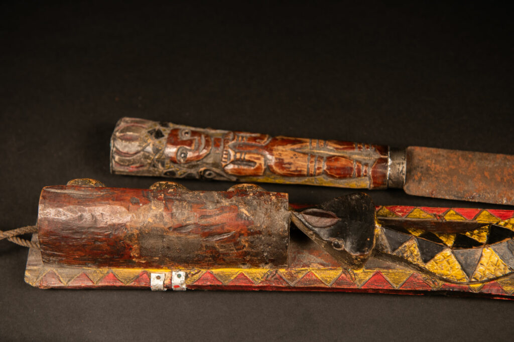 Very long Paiwan ceremonial sword featuring a scabbard carved with a snake and three human faces.