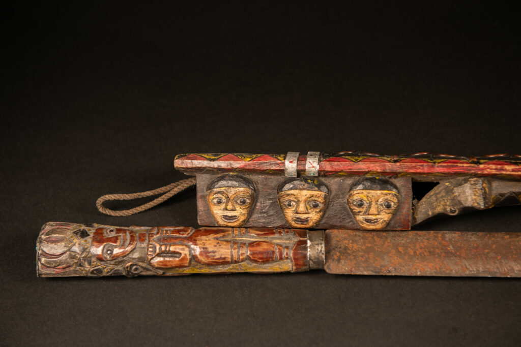 Very long Paiwan ceremonial sword featuring a scabbard carved with a snake and three human faces.