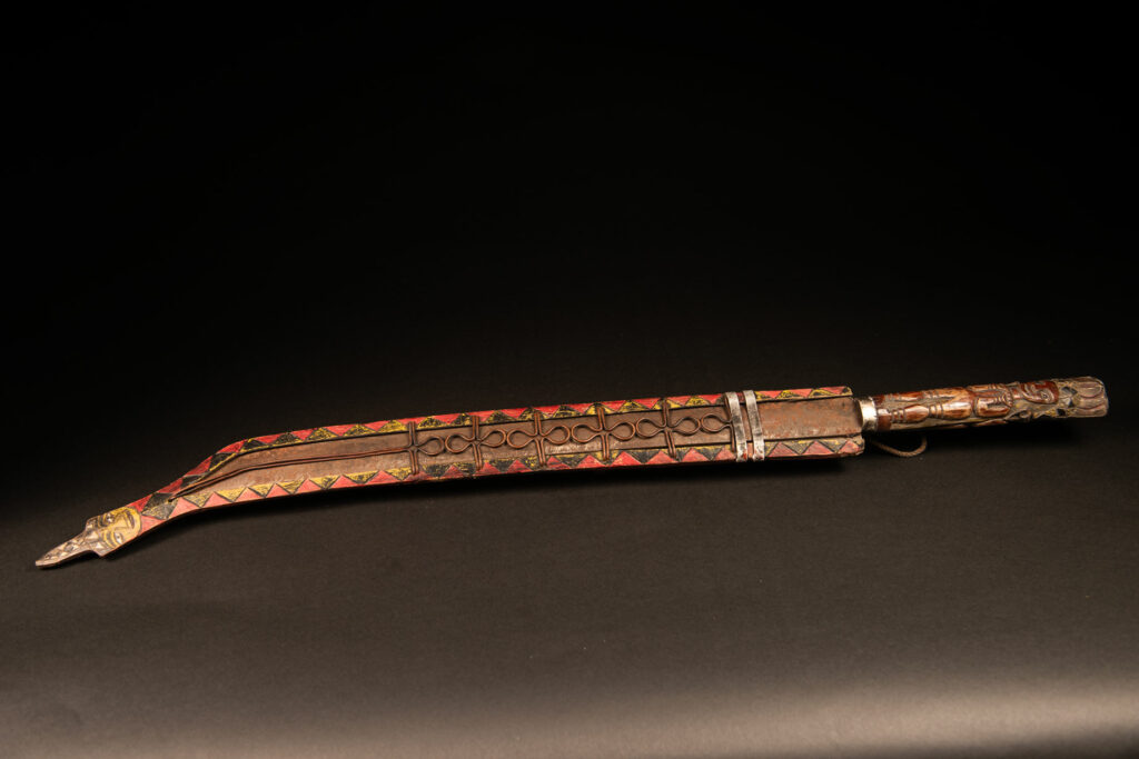 Very long Paiwan ceremonial sword featuring a scabbard carved with a snake and three human faces.