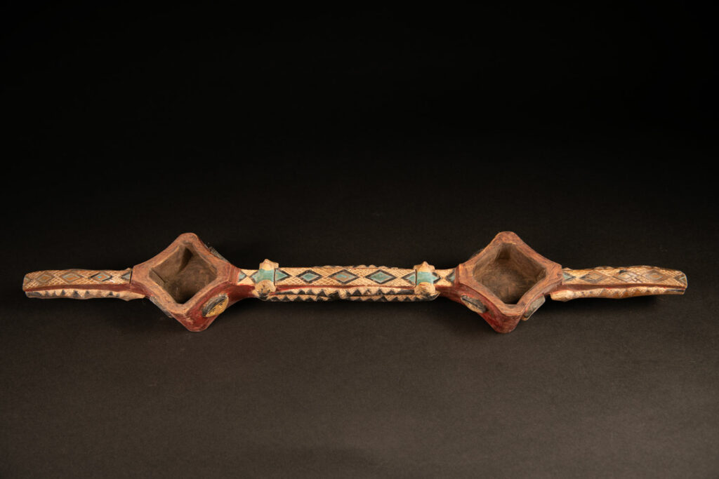 wine double cup engraved with snakes on the handles and in the center of the cup, and with human faces on the containers. The whole piece is enhanced with red, black, white, and green paint.