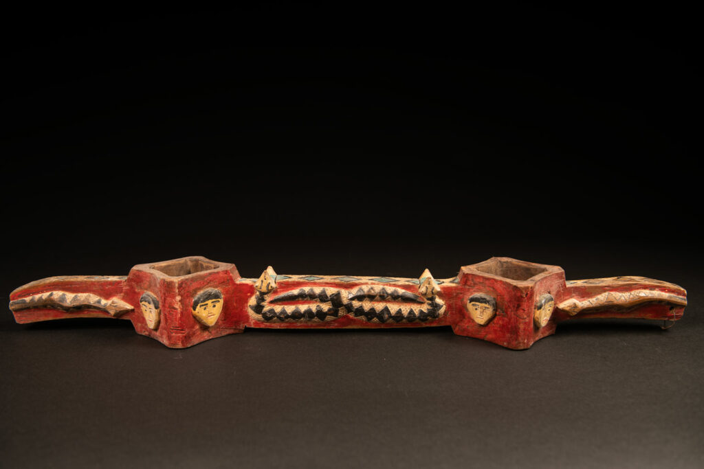 wine double cup engraved with snakes on the handles and in the center of the cup, and with human faces on the containers. The whole piece is enhanced with red, black, white, and green paint.