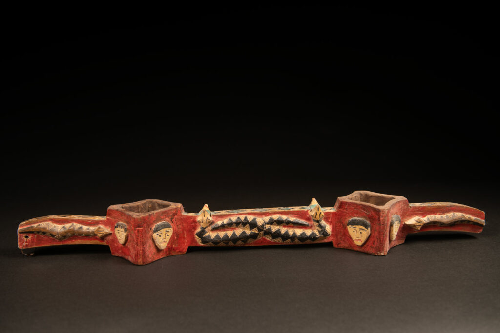 wine double cup engraved with snakes on the handles and in the center of the cup, and with human faces on the containers. The whole piece is enhanced with red, black, white, and green paint.