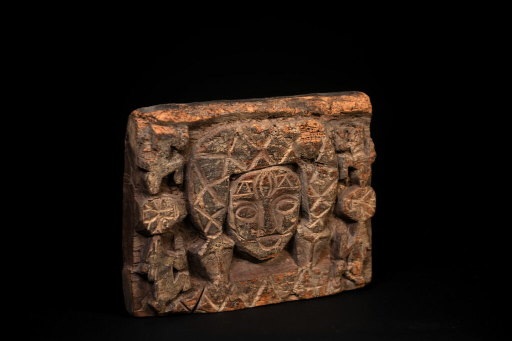 Paiwan tribe - Eave fragment carved with a central face surrounded by a sacred snake, and two faces flanked by deer.