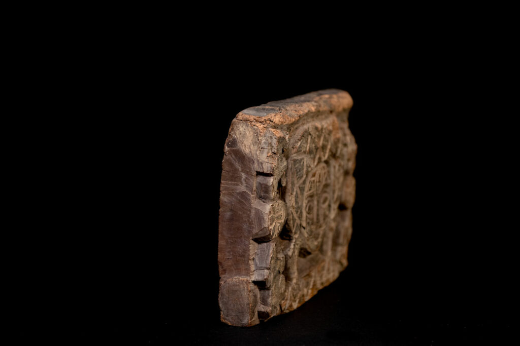 Paiwan tribe - Eave fragment carved with a central face surrounded by a sacred snake, and two faces flanked by deer.