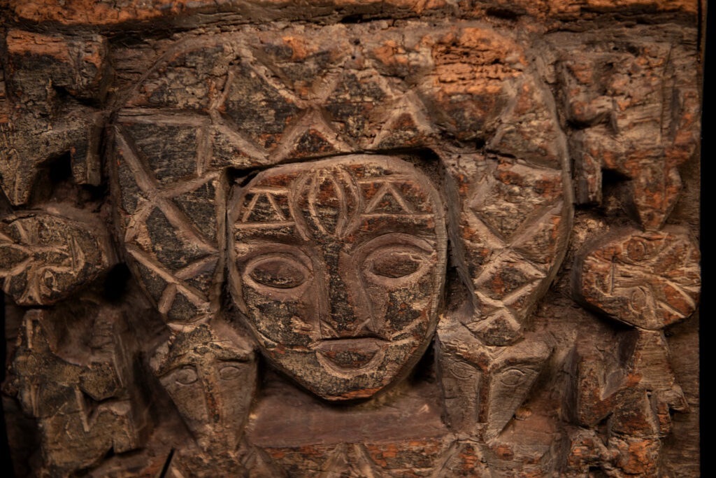 Paiwan tribe - Eave fragment carved with a central face surrounded by a sacred snake, and two faces flanked by deer.
