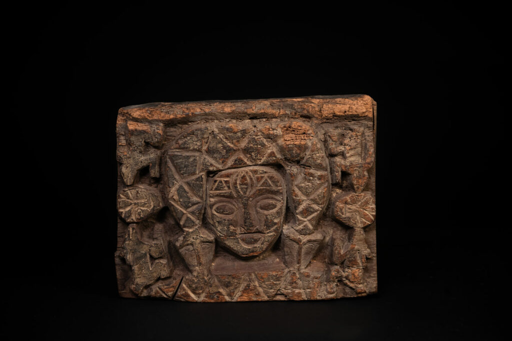 Paiwan tribe - Eave fragment carved with a central face surrounded by a sacred snake, and two faces flanked by deer.