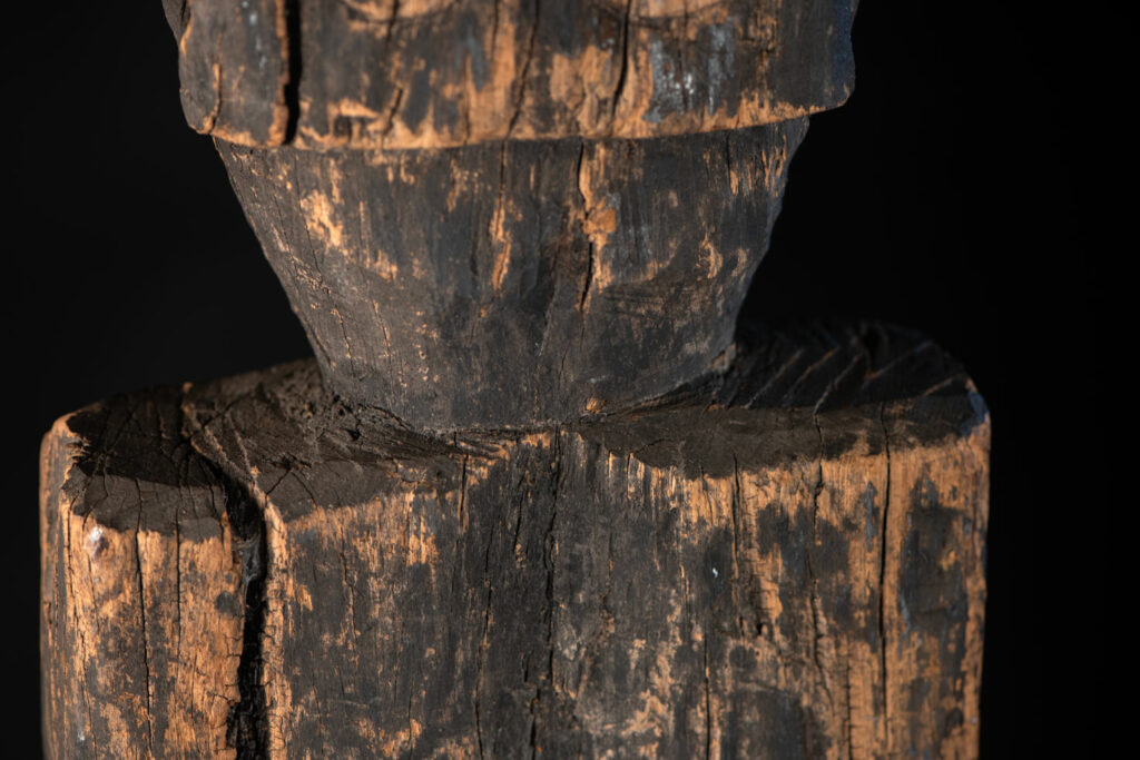 Tall ancient Paiwan tribe statue of an ancestor wearing a Paiwan dress , a hat - decoration of the hat are missing- and a bead collar.