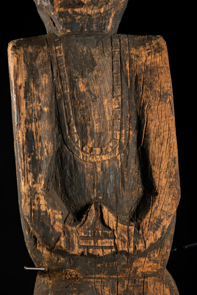 Tall ancient Paiwan tribe statue of an ancestor wearing a Paiwan dress , a hat - decoration of the hat are missing- and a bead collar.